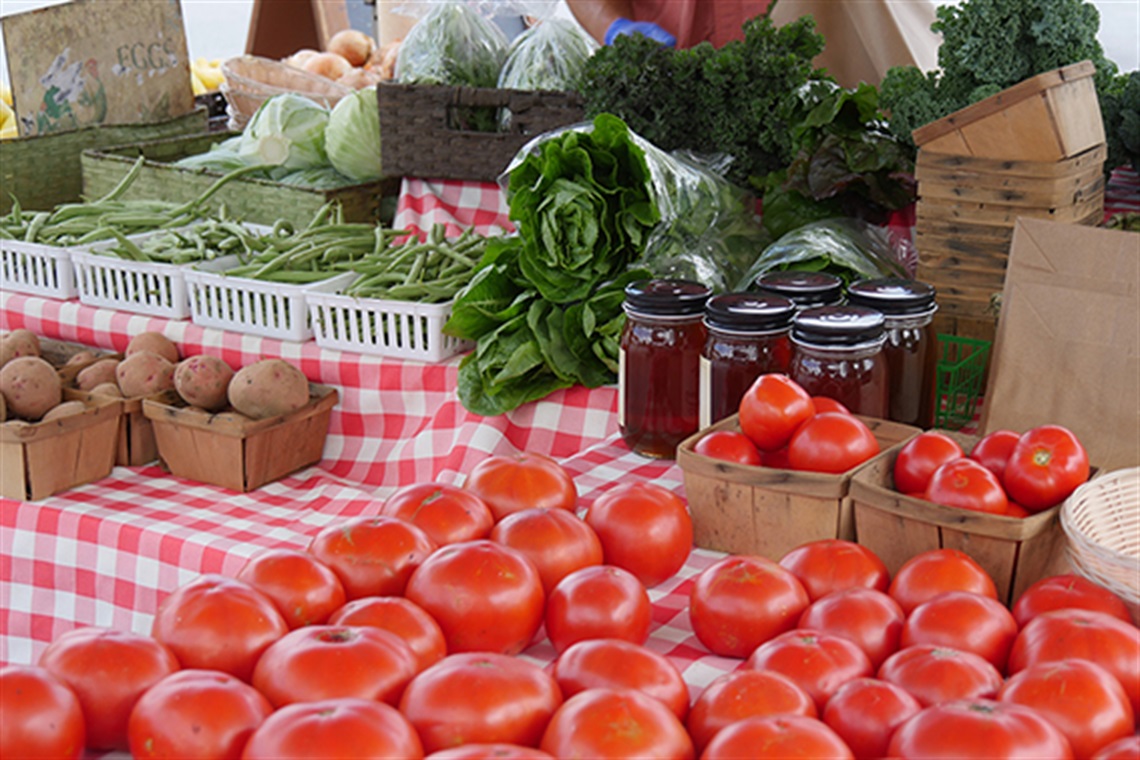 Colorful red and green fruits and vegetables on Farmers Market merchant tables.