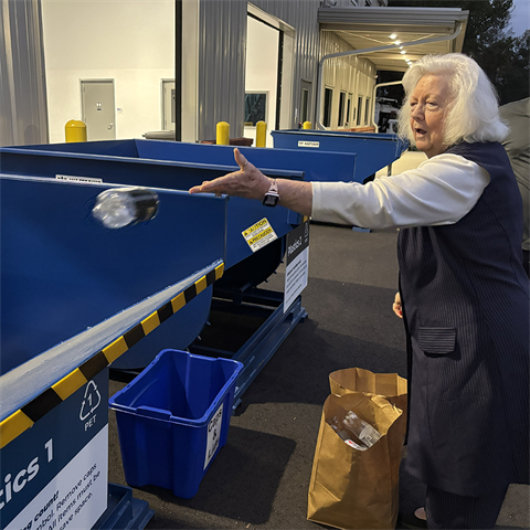 Woman throws plastic bottle into recycling bin